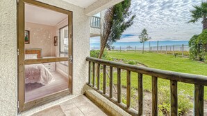 Un balcone con ringhiera in legno, vista sul mare e area verde con alberi.