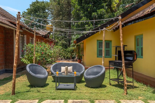 Un patio con mobili in vimini, un barbecue e una ghirlanda di luci.