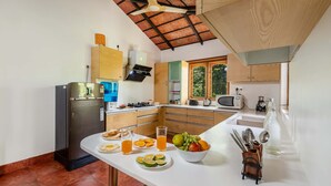 Een moderne keuken met een ingebouwde oven, magnetron en spoelbak. Op het aanrecht staat een ontbijtje met sinaasappelsap en fruit.