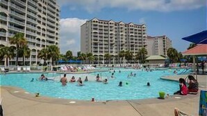 A swimming pool area with multiple levels of hotel buildings in the background. - Barefoot Landing 2BR/2BA at Willow Bend 822. Water View with Pool (North Myrtle Beach)