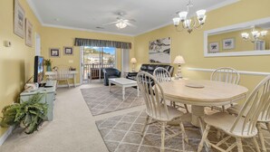 A dining area with a round table and chairs, a ceiling fan, and a chandelier. - Barefoot Landing 2BR/2BA at Willow Bend 822. Water View with Pool (North Myrtle Beach)