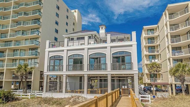 A multi-story hotel with balconies, a wooden boardwalk, and a clear sky. - Barefoot Landing 2BR/2BA at Willow Bend 822. Water View with Pool (North Myrtle Beach)