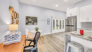 A modern kitchen with white cabinets, a stainless steel refrigerator, and a granite countertop. - Seahorse Suites #4. A Perfect Beach Getaway! (Sanibel)