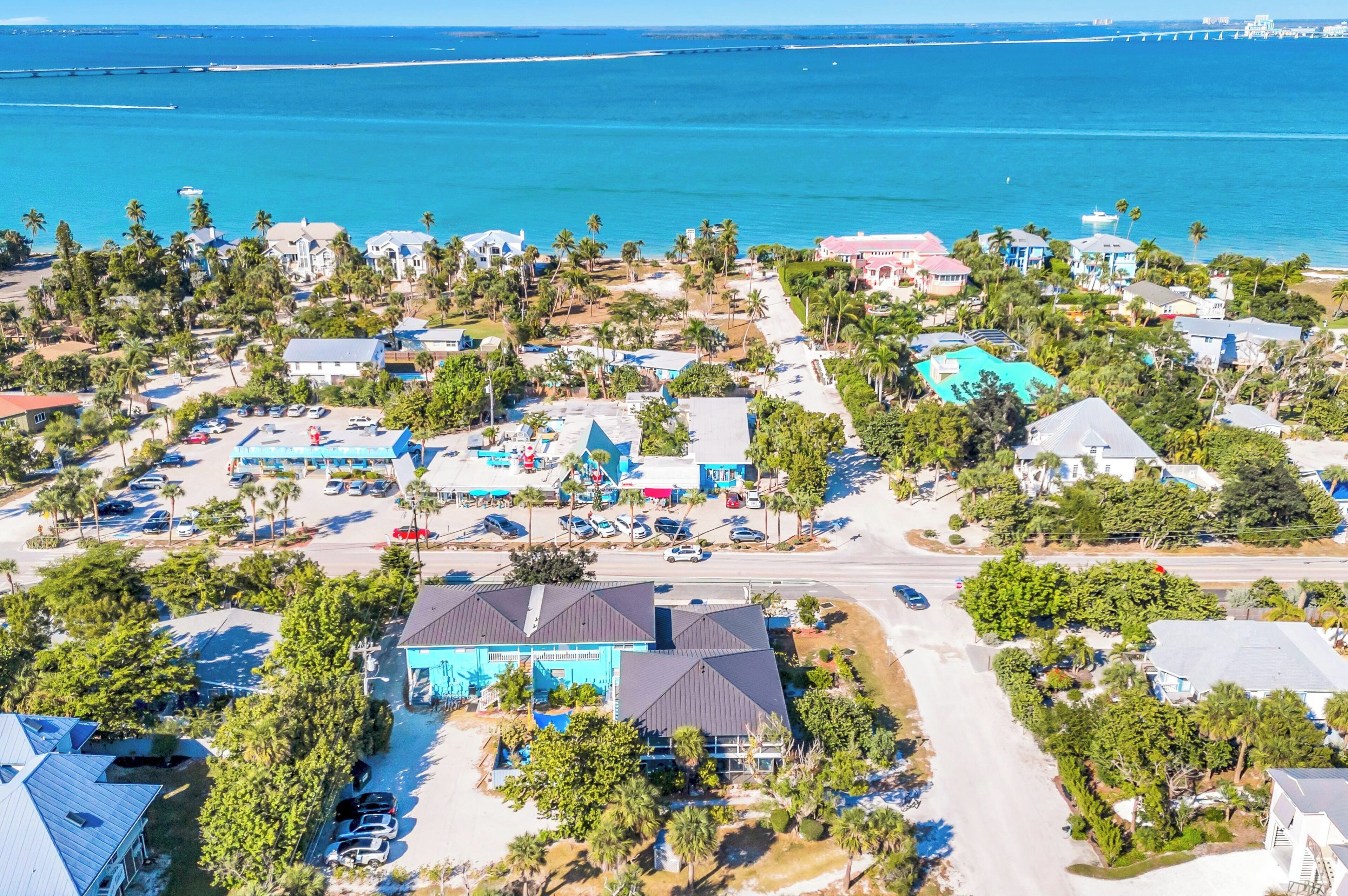 An aerial view of a coastal residential area with houses, a marina, and a beach.