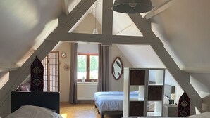 A spacious attic bedroom with three beds, wooden flooring, and a sloped ceiling with exposed beams. - Comfortable house for 12 p in rustival neighborhoud (BORGLOON)