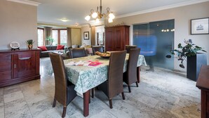A dining area with a table set for four, surrounded by wicker chairs. A wooden cabinet and a potted plant are visible in the background. - Comfortable house for 12 p in rustival neighborhoud (BORGLOON)