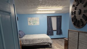 Une chambre à coucher avec un lit, une carte accrochée au mur, une grande horloge et une armoire.
