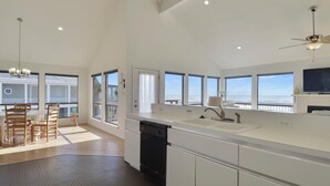 A modern kitchen with a large island, built-in dishwasher, and a view of the ocean.