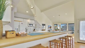 A modern kitchen with a long island counter, bar stools, and a view of the outside.