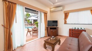 A living room with a sofa, a coffee table, a TV, and a pool view. - Sahaswara Luxury Villa Pattaya (Bang Lamung)