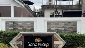 A sign for Sahaswara Luxury Villas with a modern architectural design, featuring a stone facade and a prominent logo. - Sahaswara Luxury Villa Pattaya (Bang Lamung)