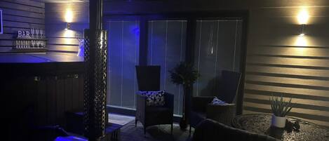 A dimly lit bar area with a wooden bar counter, a few chairs, and a table.