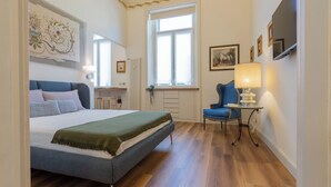 A bedroom with a bed, a chair, a table, and a window. - Studio San Michele by Wonderful Italy (Turin)