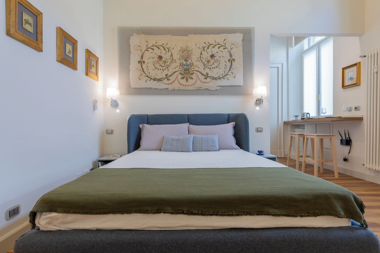 A bedroom with a bed, a desk, and a radiator.