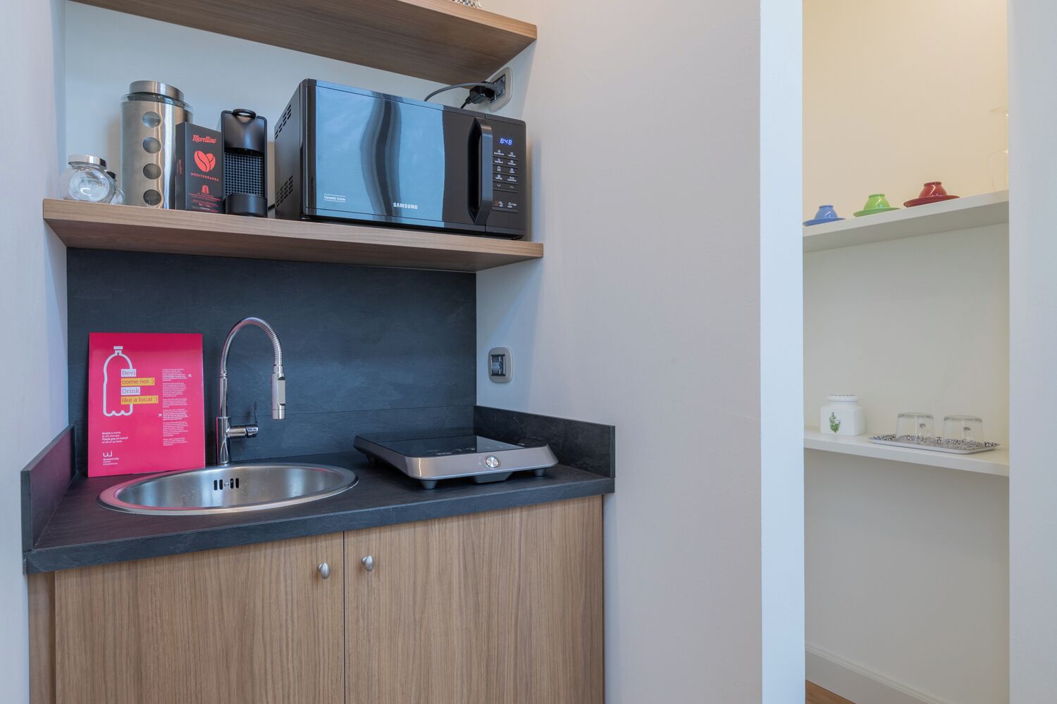 A compact kitchen with a built-in microwave, a stainless steel sink, and a small countertop.