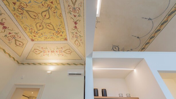 A room with a decorative ceiling featuring floral patterns and a modern light fixture. - Studio San Michele by Wonderful Italy (Turin)