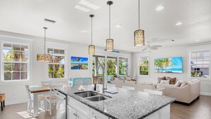 A spacious kitchen with a large island, white cabinetry, and pendant lighting. - Anna Maria Home with Pool and Rooftop Deck! 5-min Walk to Beach - Coconut Breeze (Anna Maria)