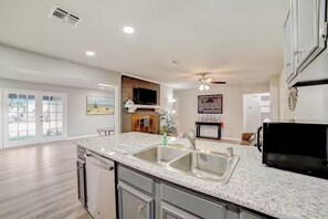 A spacious kitchen with a granite countertop, stainless steel sink, and a black refrigerator.