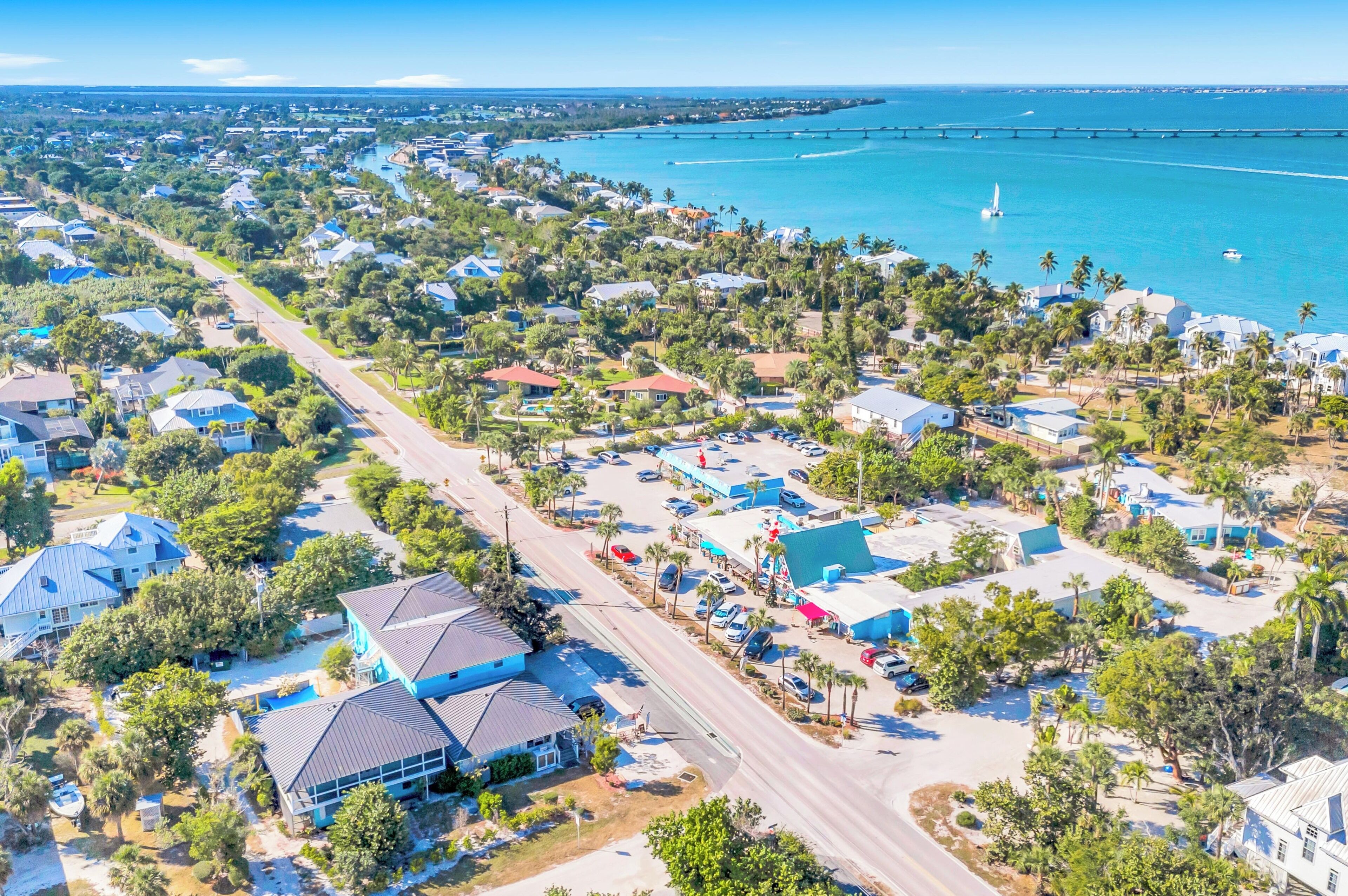 An aerial view of a coastal residential area with houses, roads, and a bridge.