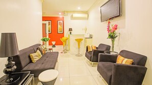 A modern living room with grey sofas, a coffee table, and a TV mounted on the wall. - Townhouse Oak VIP Suites, Evangelista Makati Manila (Makati)