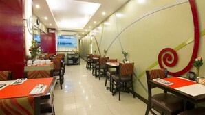 A restaurant with multiple tables and chairs, a modern ceiling design, and a view of the outside. - Townhouse Oak VIP Suites, Evangelista Makati Manila (Makati)