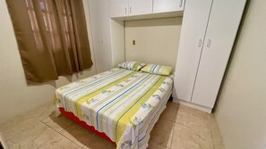 Een slaapkamer met een bed, een kledingkast en een gordijn.