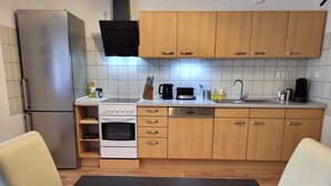 A modern kitchen with wooden cabinets, a stainless steel refrigerator, an oven, and a dishwasher.