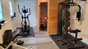 A home gym with exercise equipment, including a stationary bike, elliptical, and weightlifting station.