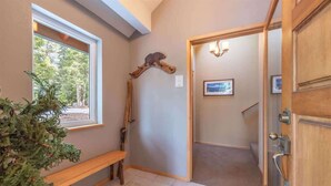 A hallway with a wooden bench, a wooden coat rack, and a door leading to another room. - The Jay Chalet (Tahoe City)