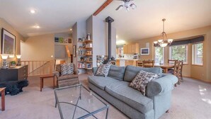 A spacious living room with a sofa, coffee table, and a staircase leading to another level. - The Jay Chalet (Tahoe City)