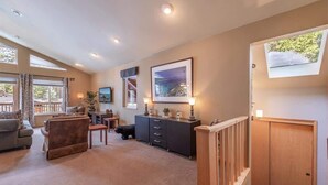 A spacious living room with a sofa, a coffee table, and a cabinet. There is a window with curtains and a picture on the wall. - The Jay Chalet (Tahoe City)