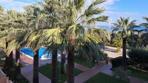Zona de piscina rodeada de palmeras y cielo despejado.