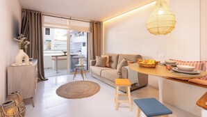 Un salon moderne avec un canapé, une table à manger et un luminaire suspendu.