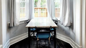 A dining area with a table and chairs, large windows with white curtains, and a wooden ceiling. - Luxurious Loft Inspired Living (Montgomery)