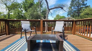 A wooden deck with two chairs and a table, surrounded by a wooden fence and trees. - Luxurious Loft Inspired Living (Montgomery)