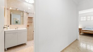 Een moderne badkamer met een witte wastafel, een grote spiegel en een douche.