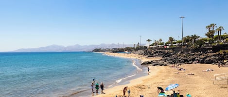 A beach with people sunbathing and walking along the shore.