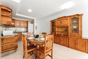 Una cocina con armarios de madera, una mesa de comedor, sillas, un microondas y un fregadero.
