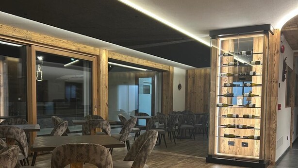 Un espace de détente moderne doté d’un foyer central, de meubles en bois et d’un meuble vitrine pour présenter les bouteilles de vin.