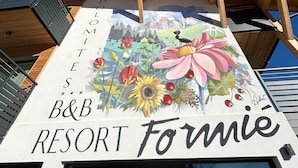 Un bâtiment orné d’une fresque colorée représentant des fleurs et d’une enseigne indiquant « B&B RESORT Fornie ».