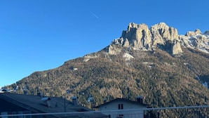 Un bain à remous avec une vue sur les montagnes, entouré de bâtiments et d’une clôture.