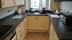 A kitchen with a stove, sink, and cabinets.