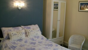 A bedroom with a bed, a wardrobe, and a chair.