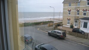 A coastal road with cars, a beach, and a building with a brick facade.
