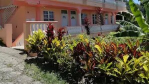A multi-story building with balconies, surrounded by tropical plants. - Louislyn Apartments #8 Quiet and Scenic (Picard)