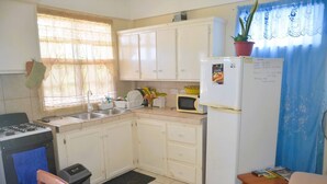 A compact kitchen with white cabinets, a stove, a sink, a microwave, and a refrigerator. - Louislyn Apartments #8 Quiet and Scenic (Picard)