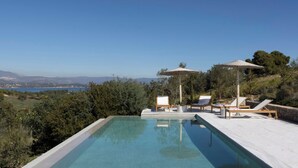 A pool with lounge chairs and umbrellas overlooking a scenic landscape.