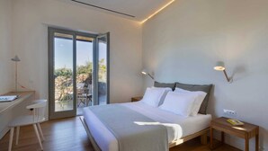 A bedroom with a bed, a desk, and a chair. There is a sliding glass door leading to an outdoor area with a table and chairs.