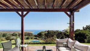 A covered outdoor seating area with a view of the ocean and a pool. - SeaView Oasis: 4BR, Pool, Tennis by Host For Us (Alcabideche)