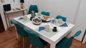 A dining table with chairs, a basket, plates of food, cups, and a remote control. - Family apartment near the Vatican. Well connected. 2 terraces. WIFI. (Roma)